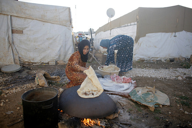 Two women cook at a Syrian refugees camp on June 18, 2014 in the Lebanese village of Zahle in the Bekaa valley. Photo by Matthieu Alexandre for Caritas Internationalis