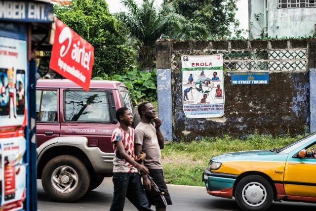 People walk past a Caritas Ebola poster on Savage Street. Tommy Trenchard/Caritas