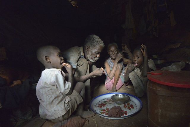 A family shares a meal inside their shelter in a camp