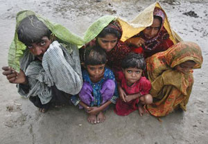 Family members, displaced by floods, use a tarp to escape a monsoon downpour while taking shelter at a make-shift camp for flood victims in the Badin district in Pakistan's Sindh province September 14, 2011. Floods this year have destroyed or damaged 1.2 million houses and flooded 4.5 million acres (1.8 million hectares) since late last month, according to officials and Western aid groups. More than 300,000 people have been made homeless and about 200 have been killed. Credits: REUTERS/Akhtar Soomro