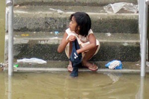 A girl washes clothes in flood water. CRS Philippines is procuring water containers and hygiene kits in other parts of the country for distribution to flood victims. Credits: NASSA-Caritas Philippines