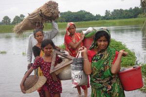 In a flooded area in Bangladesh, people salvage their household items and carry them in buckets. Credits: Caritas Bangladesh