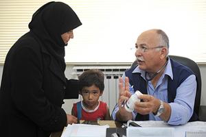 Caritas Doctor, Akaf Khalil Alusi with his patient and mother at Caritas clinic in Zarqa, Jordan near Amman. The clinic is caring for Syrian refugees. Credits: Caritas Jordan