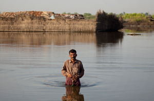 A man wades through floodwaters to reach his family's makeshift camp in a village in Sindh province, Pakistan. Credits: Asaid Zaidi / Caritas