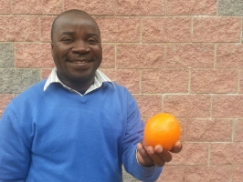 Carsterns Mulume, Directeur national de CADECOM, tient une orange lors d’une réunion « de la nourriture pour tous » à Rome, en Italie. Photo: Laura Sheahen / Caritas