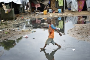 A boy navigates a flooded portion of a camp for internally displaced families located inside a United Nations base in Juba, South Sudan. Photo by Paul Jeffrey for Caritas  