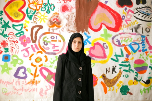 Amar, 18, a newly arrived Syrian refugee woman victim of a trauma, poses on June 19, 2014 at Caritas Migrant Center in Dahr El Ain, near Tripoli. Amar is catatonic and didn't speak for the last 6 months. The background shows a drawing made by 100 women for the Women's Day on March 8, 2014. Credit: Matthieu Alexandre/Caritas