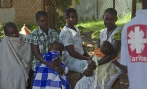 Mothers wait in line, as their young ones lay asleep in their arms, during an aid distribution in Yambio, South Sudan. Credit. Caritas