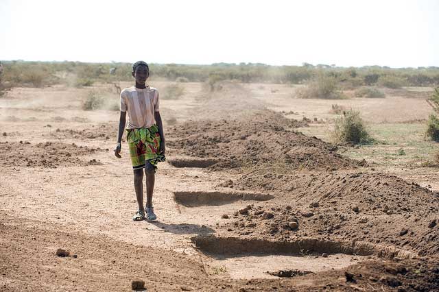 A local youth walks by a series of holes known as micro basis that are part of a CI-supported water project in Ethiopia's arid Jijiga Zone. Photo by David Snyder/Caritas 
