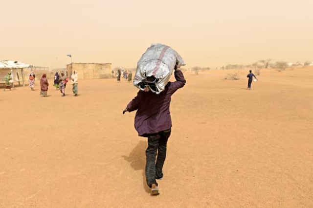 A Malian refugee takes charcoal to the tent where he's staying with his family. Photo by Simone Stefanelli/Caritas