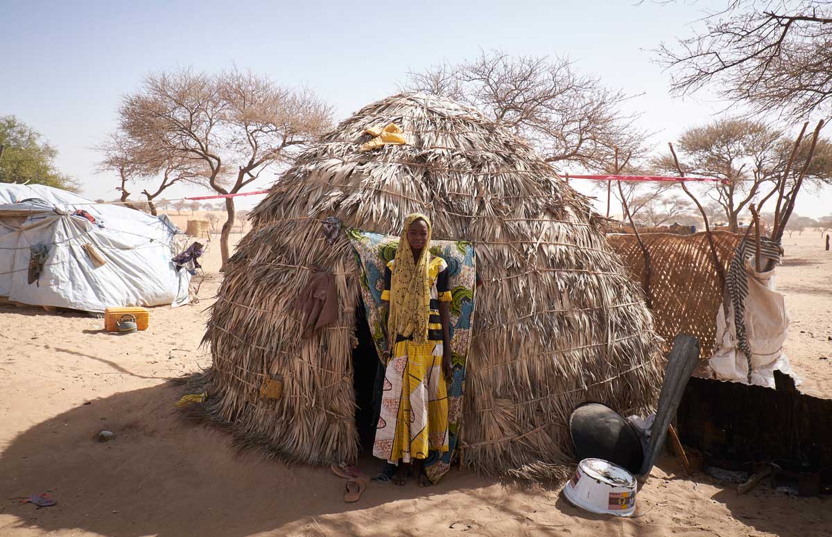 Fatima Brah, 16 years old (yellow) stands outside a shelter in the village of Guidan Kaji near the border with Nigeria on the outskirts of Diffa, Niger on February 13, 2016. Photo by Sam Phelps/Caritas