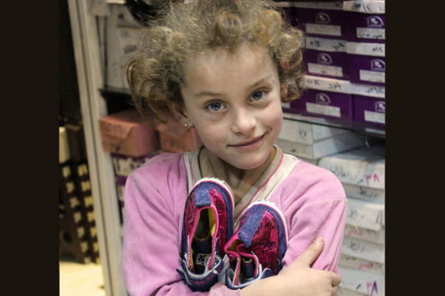 Fatimah, de 6 años, y sus zapatos nuevos, comprados con el cupón Caritas.