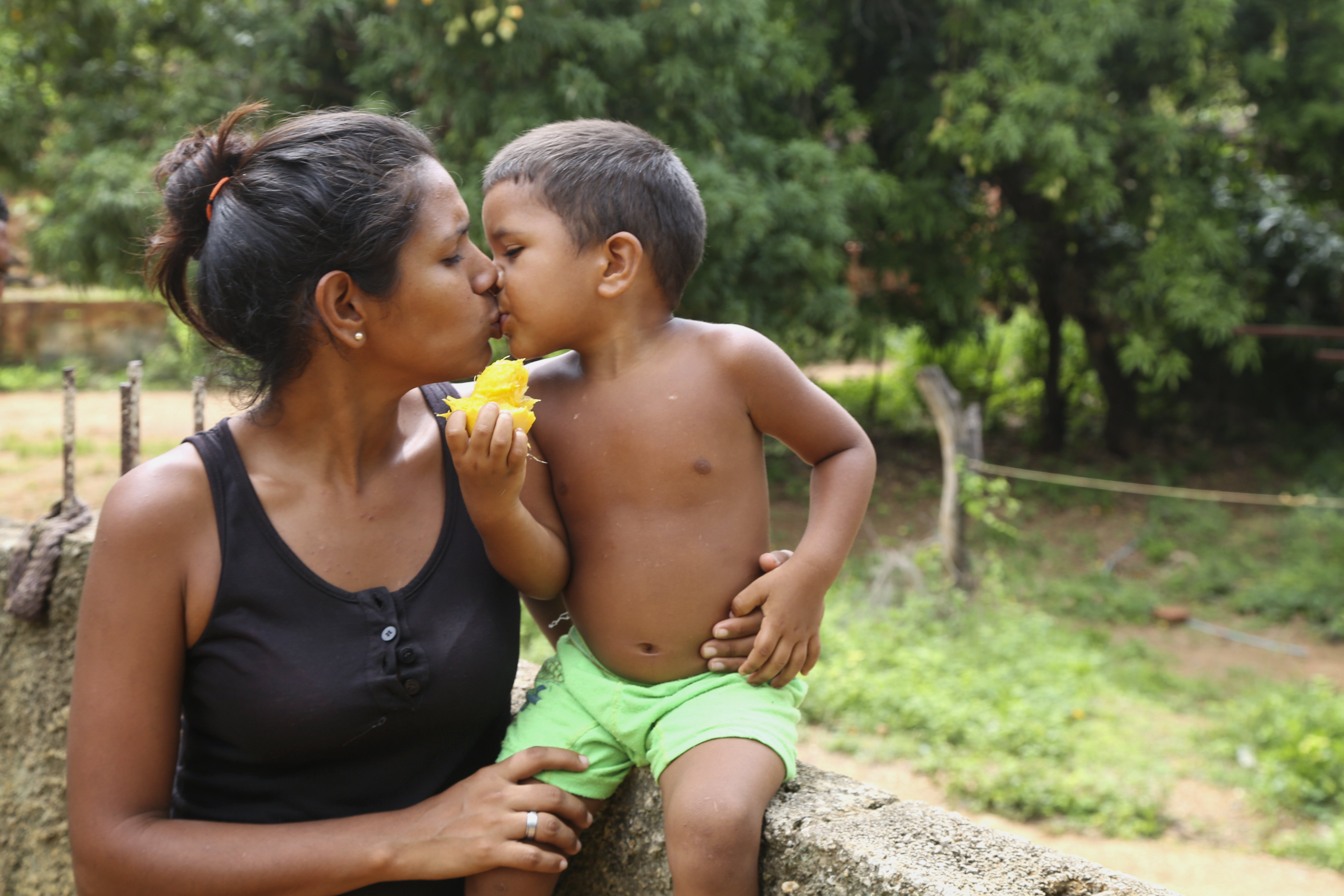 Yusmarelis Acua, 29, gets a kiss from her son Greivis, 3, outside their home in Venezuela.