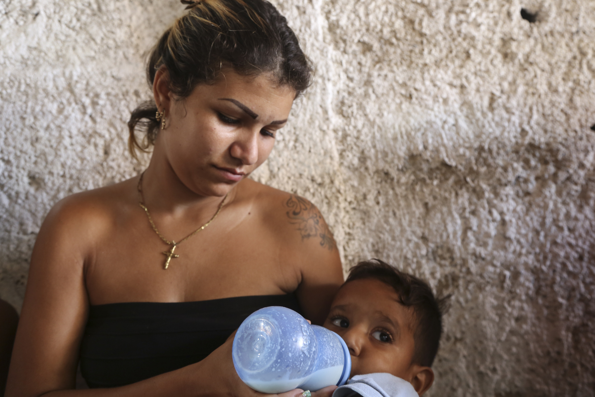 Claribel Morales, mother of 3, feeds her youngest son, Yordin, nutrialimento while she waits to have his growth monitored by Caritas Venezuela volunteers.